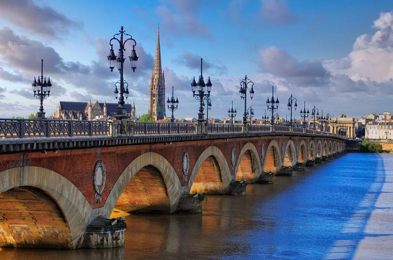 Le pont de Pierre à Bordeaux au lever du soleil, avec la flèche de la basilique Saint-Michel en arrière-plan