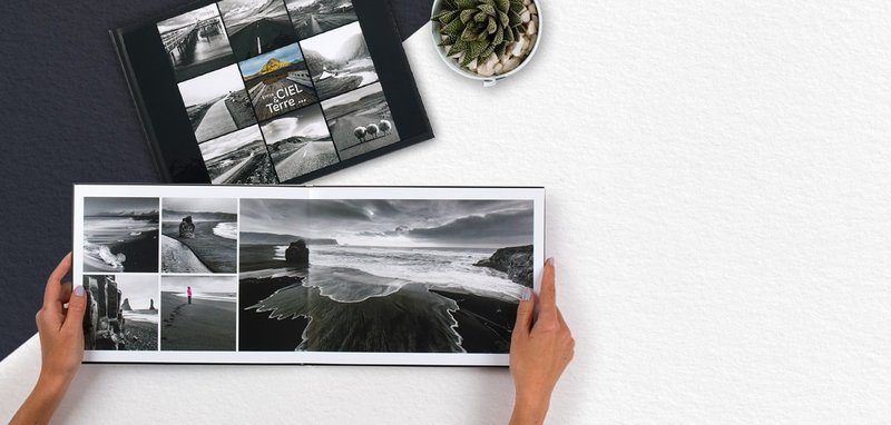 Un livre photo en noir et blanc ouvert sur une table avec des photos de paysages marins.