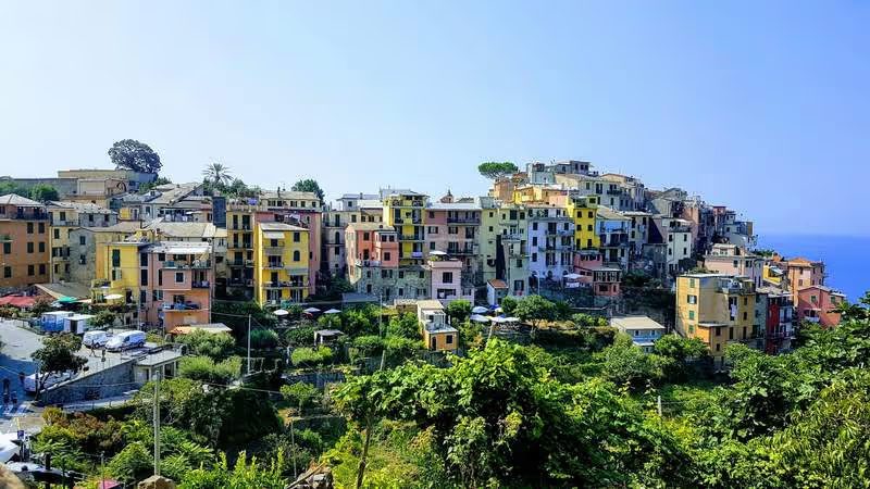Vue pittoresque de Corniglia, un village perché sur une colline avec des maisons colorées et une végétation luxuriante.