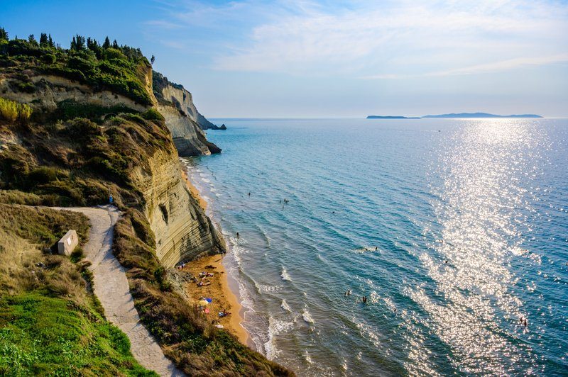 Vue sur Loggas Beach, ses falaises imposantes et la mer scintillante au coucher du soleil.