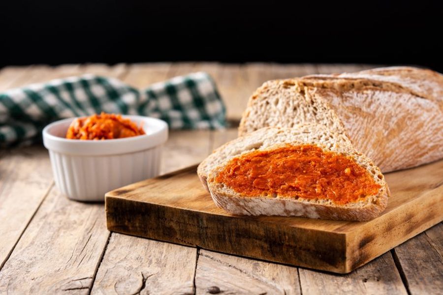 Pain frais tartiné de sobrasada sur une planche en bois, une spécialité locale de Majorque.