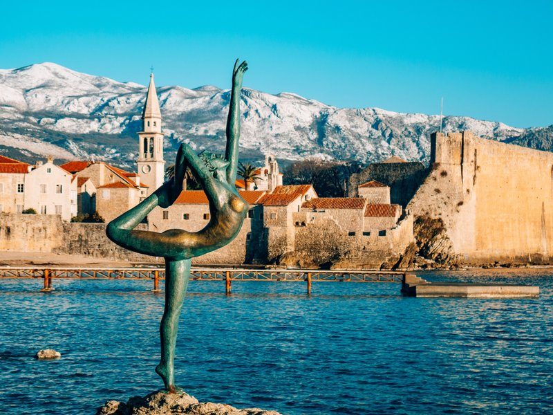 Statue de la ballerine face à la vieille ville de Budva et montagnes en arrière-plan