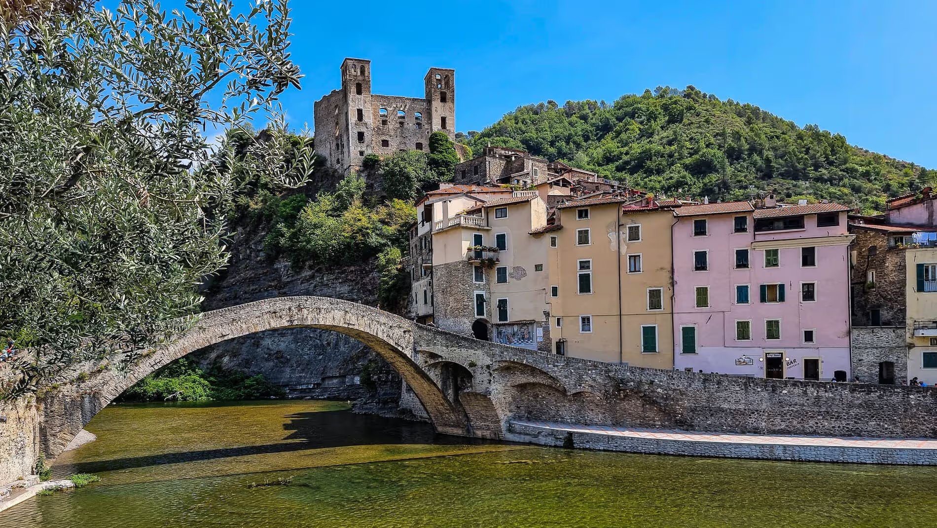 Vue du pont médiéval et du château des Doria à Dolceacqua, Italie, avec des maisons colorées en arrière-plan.