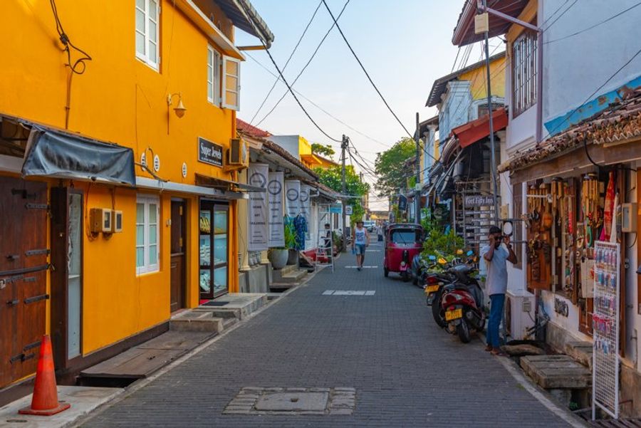 Ruelle colorée avec boutiques artisanales et tuk-tuks dans le fort de Galle