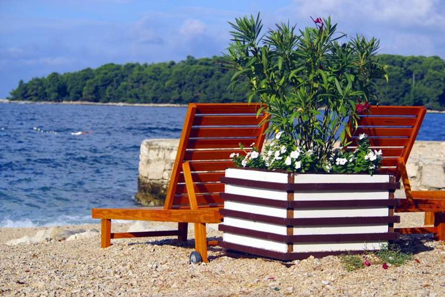 Transats en bois sur une plage de galets à Rovinj, avec une vue sur la mer Adriatique.