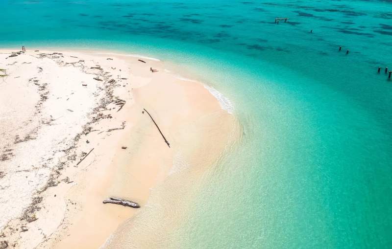  Vue aérienne d'une plage de sable blanc avec une mer turquoise à Koh Lipe, Thaïlande. Quelques personnes sont visibles au loin, profitant de la tranquillité de la plage isolée. ​