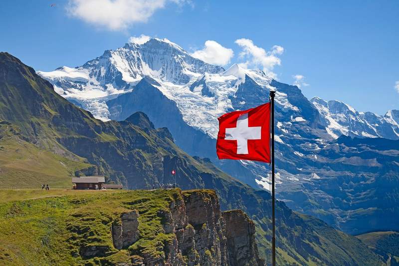 Drapeau suisse flottant face aux sommets enneigés des Alpes bernoises en Suisse