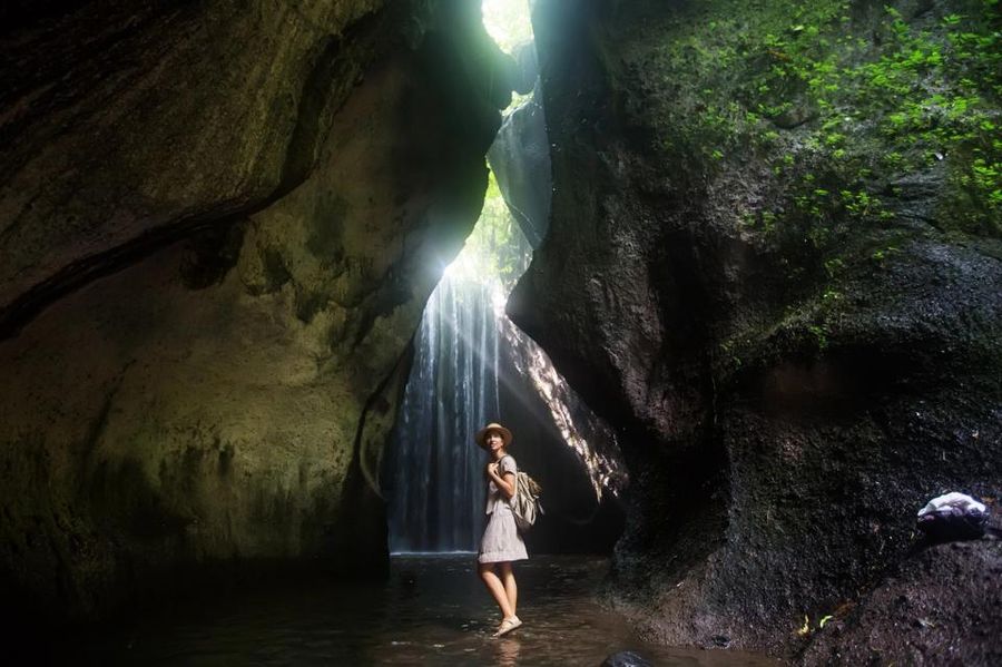 Visiteur explorant la cascade cachée de Tukad Cepung entourée de formations rocheuses à Sidemen.