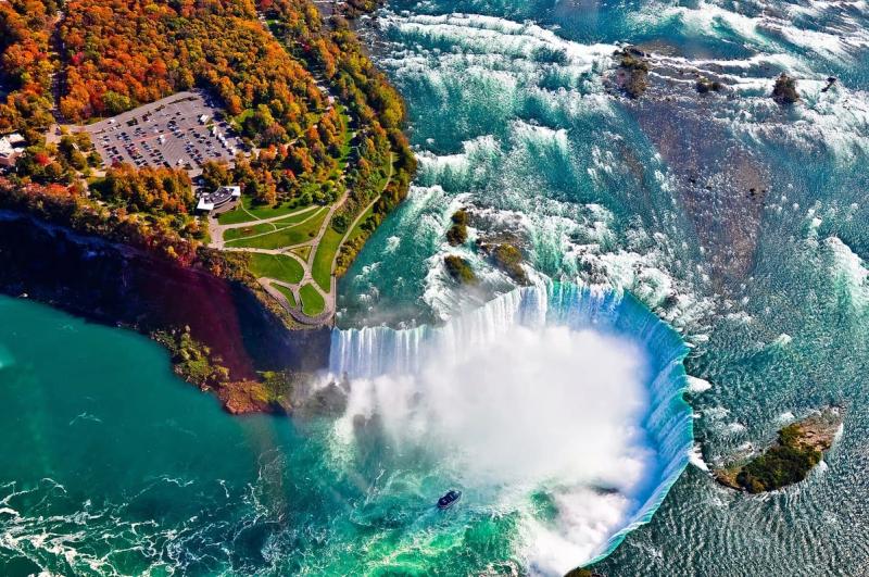 Vue aérienne des chutes du Niagara avec des eaux tumultueuses, une brume dense et un parc verdoyant à proximité
