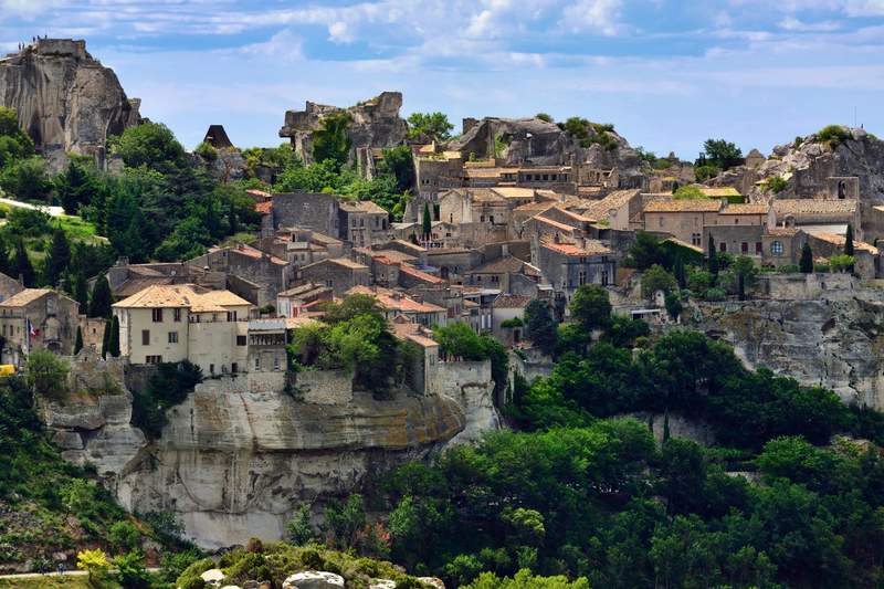 Vue panoramique du village perché des Baux-de-Provence, avec ses maisons en pierre, ses falaises blanches et la végétation des Alpilles en été