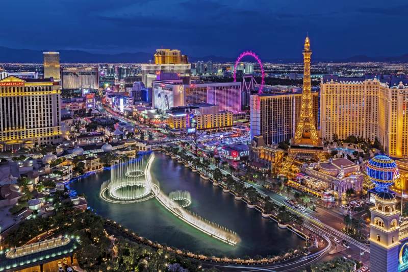 Vue nocturne de Las Vegas avec les fontaines du Bellagio, la réplique de la Tour Eiffel du Paris Las Vegas et les lumières éclatantes du Strip.