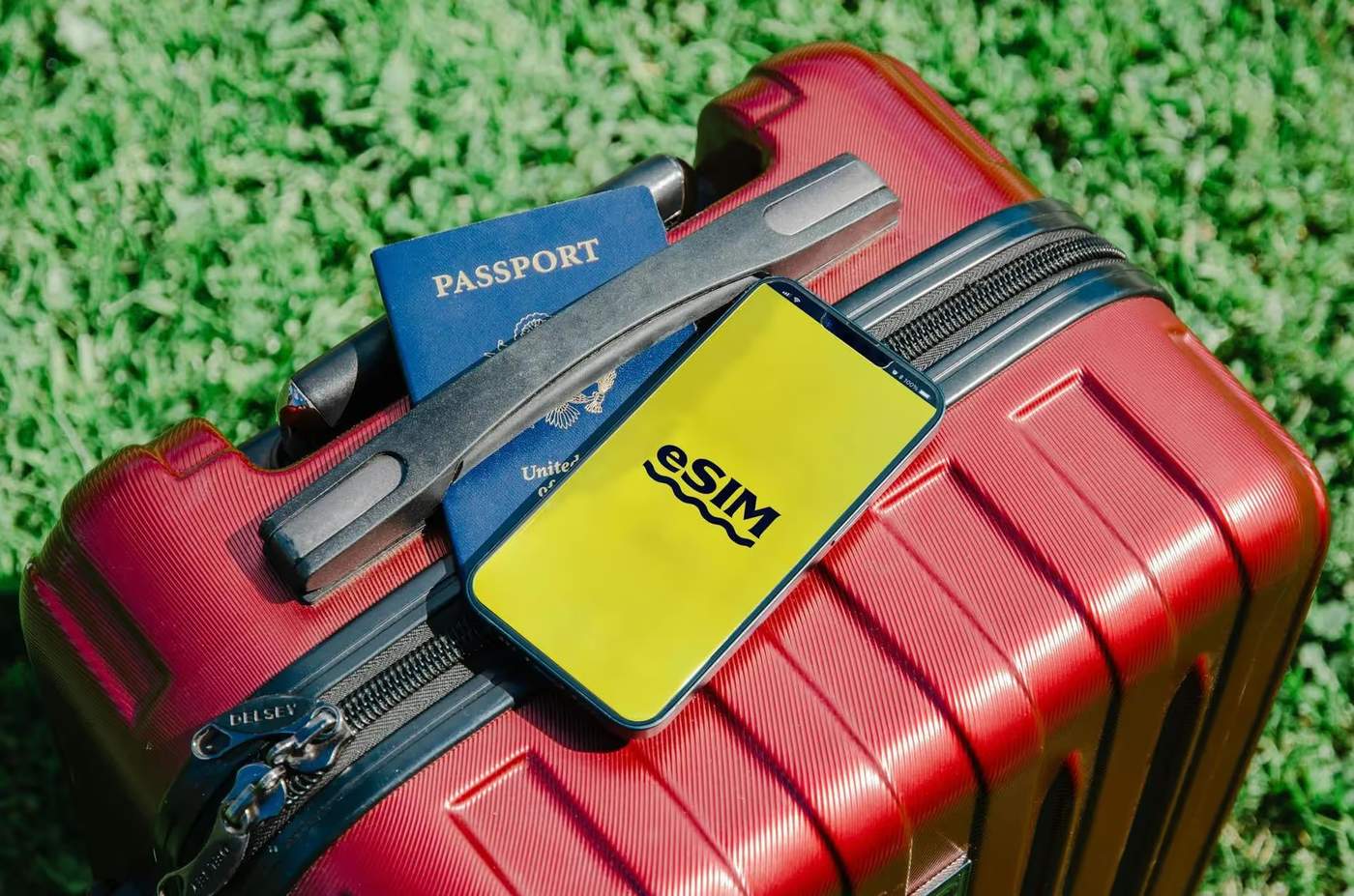 Valise rouge avec passeport et téléphone affichant 'eSIM', prêt pour le voyage.