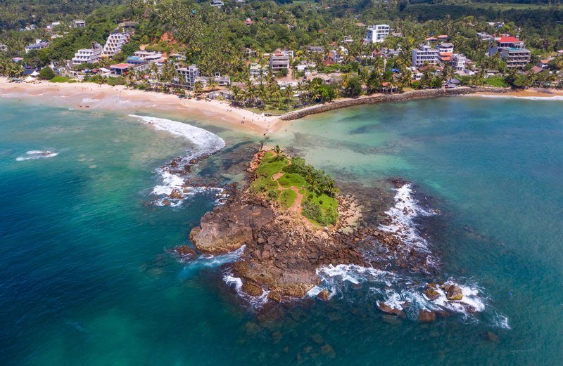 Vue aérienne de Parrot Rock à Mirissa, un petit îlot rocheux recouvert de végétation, entouré d