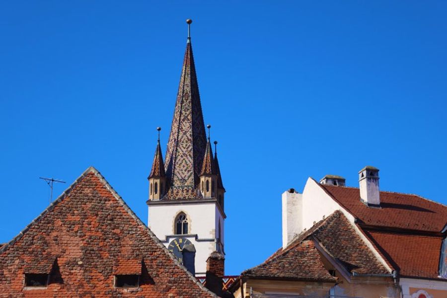 Clocher coloré de la cathédrale évangélique de Sibiu se détachant sur un ciel bleu.