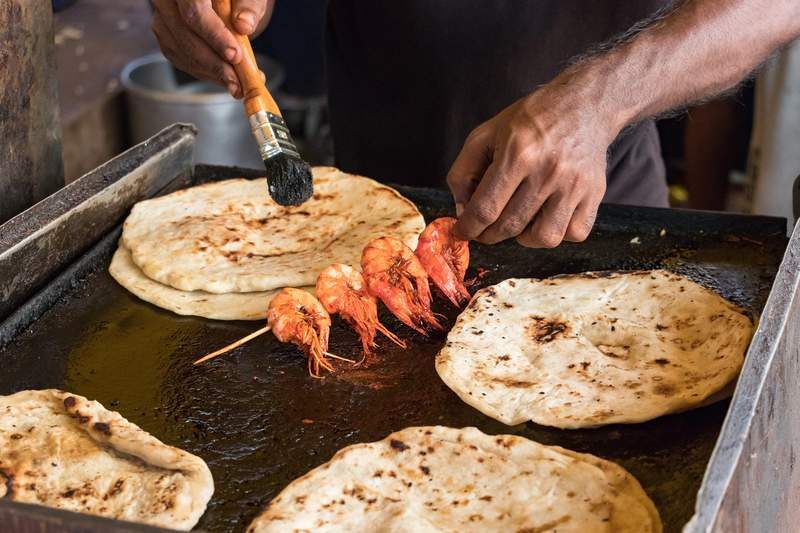 Pain roti et brochette de crevettes grillées sur un stand de street food à Colombo.