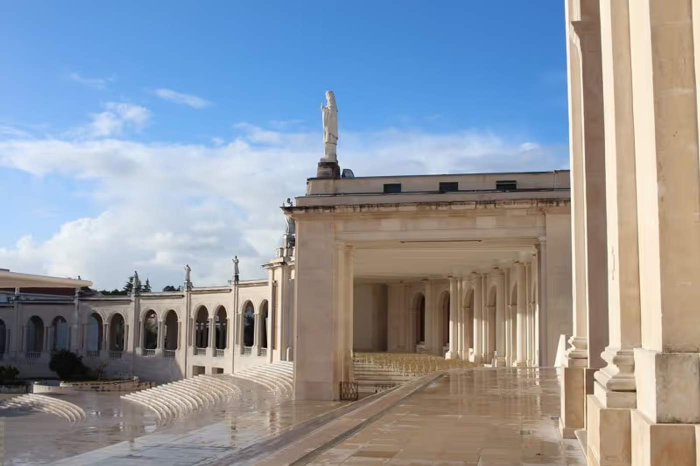 Vue partielle du sanctuaire de Fatima avec ses colonnes et ses statues sous un ciel bleu, Portugal.