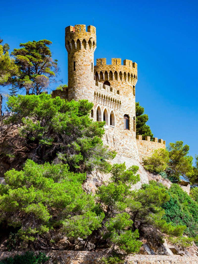 Ancien château de Sant Joan perché sur une colline verdoyante à Blanes, Espagne, offrant une vue imprenable.