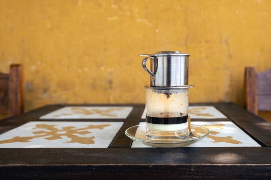 Café vietnamien avec filtre en inox sur fond de mur jaune à Hoi An