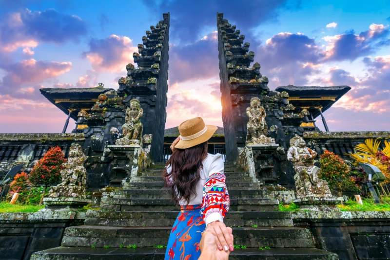 Femme tenant la main de son partenaire devant le Handara Gate au coucher du soleil à Munduk, Bali.