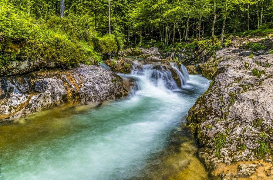 Cascade aux eaux turquoise de la rivière Mostnica dans les gorges de Bohinj, encadrée de rochers et d