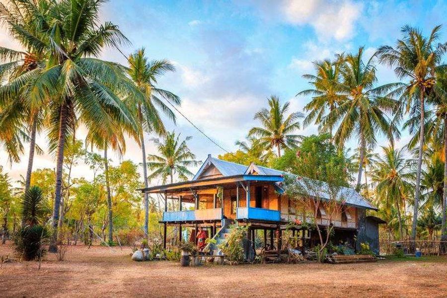 Maison traditionnelle entourée de palmiers à Gili Air, Bali.