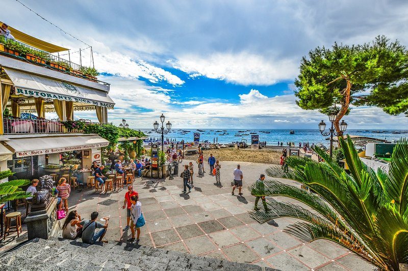 Scène animée à la Marina Grande de Positano avec des restaurants et des bateaux.