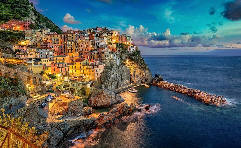 Vue pittoresque de Riomaggiore avec un magnifique coucher de soleil illuminant le village et la mer.