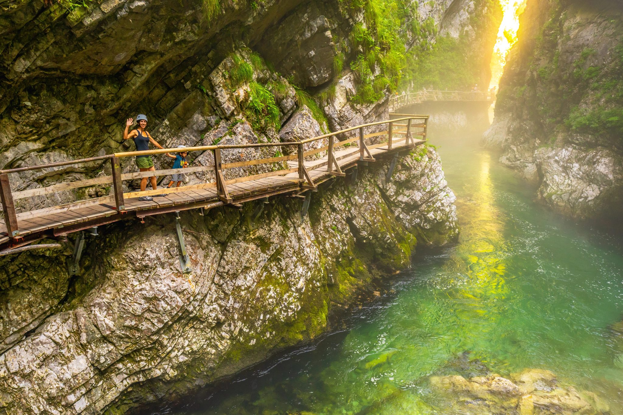 Des visiteurs portant un casque empruntent une passerelle au-dessus de la Radovna dans les gorges de Vintgar.