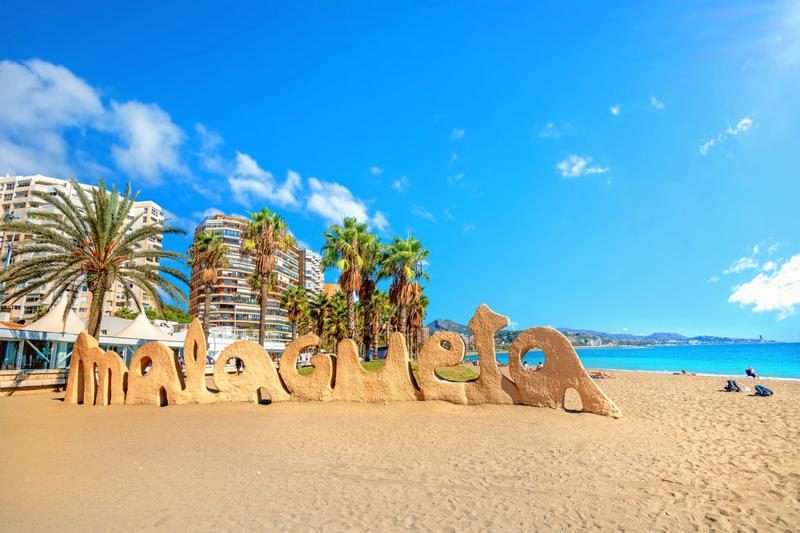 Plage de la Malagueta avec des sculptures de sable et des palmiers.