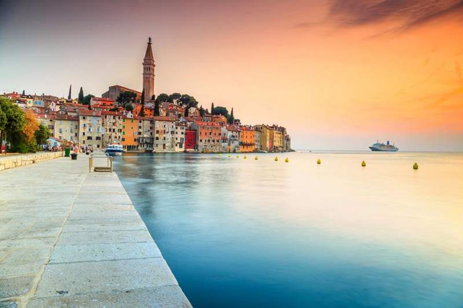 Quai pittoresque avec vue sur les maisons colorées de Rovinj au coucher du soleil.