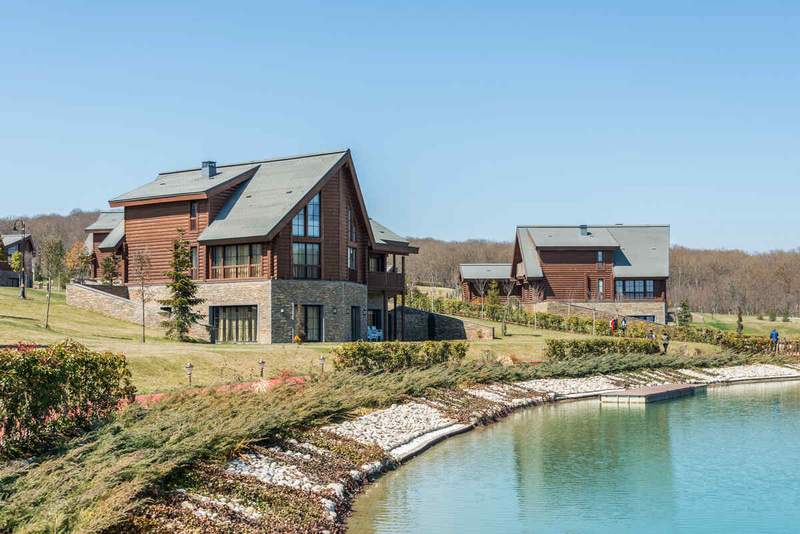 Chalets en bois d'une résidence de vacances au bord d'un lac avec pelouse verdoyante