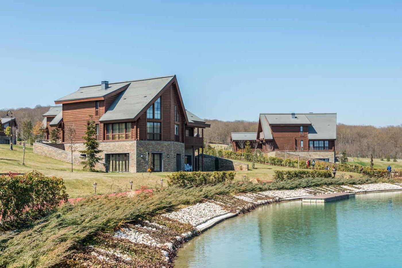 Chalets en bois d'une résidence de vacances au bord d'un lac avec pelouse verdoyante