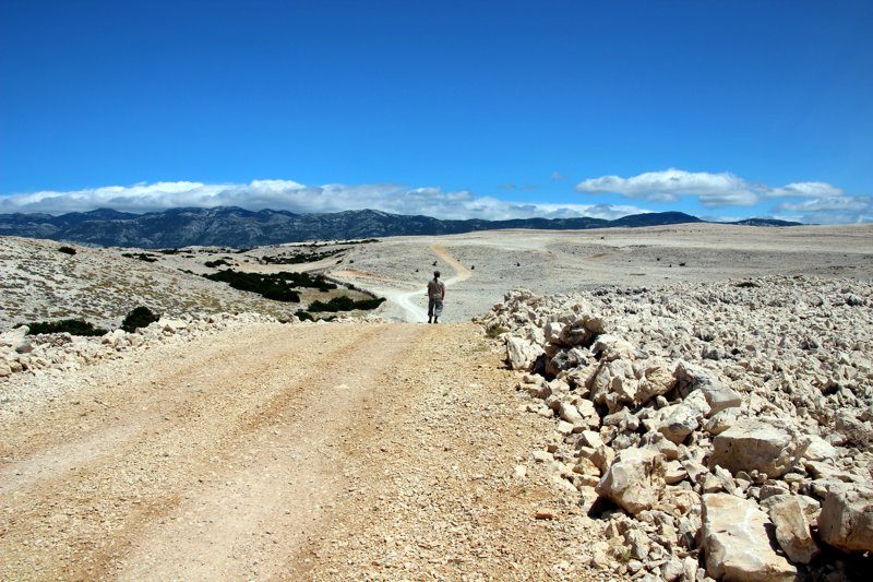 Un chemin de randonnée dans le paysage lunaire du triangle de Pag, entouré de roches sèches et d