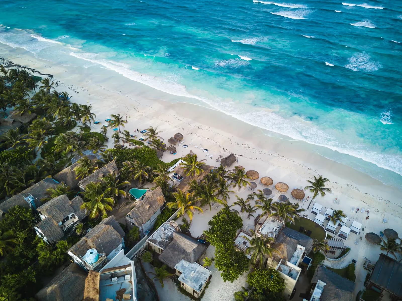 Une plage, des maisons et des palmiers à Tulum