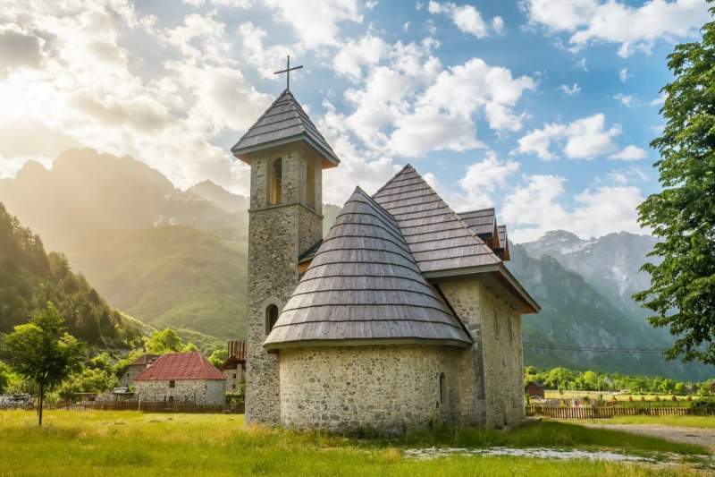 Église pittoresque de Theth entourée des montagnes majestueuses des Alpes albanaises.