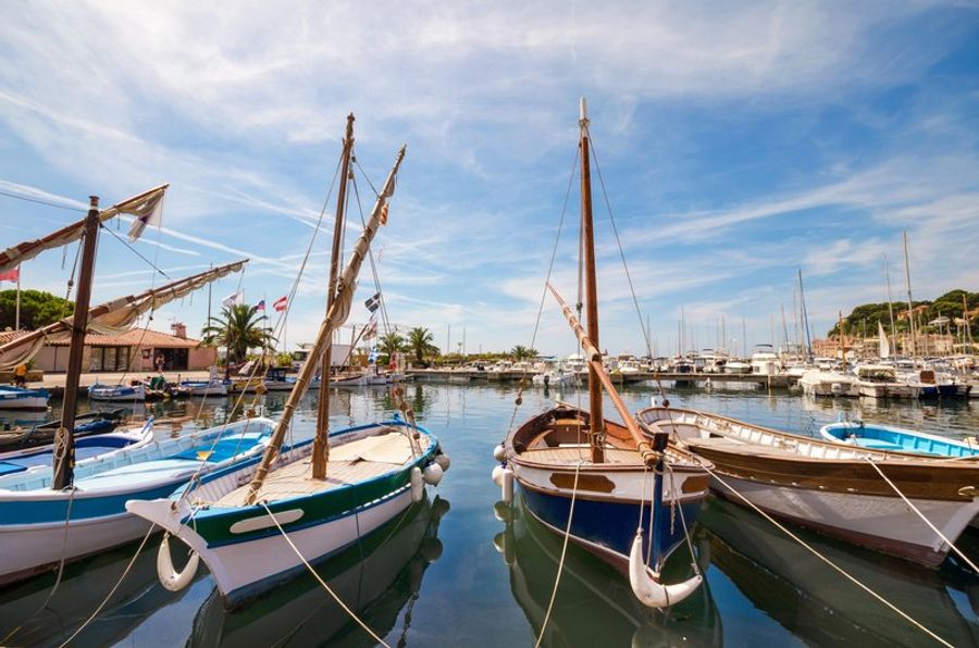 Port pittoresque de Sanary-sur-Mer avec des bateaux traditionnels et des bâtiments colorés.