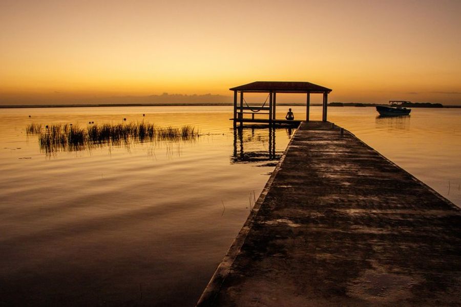 Ponton en bois avec cabane et hamac sur la lagune de Bacalar au lever du soleil