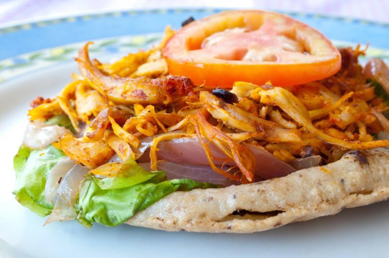 Plat mexicain traditionnel avec poulet mariné, légumes frais et tranches de tomate sur une tortilla