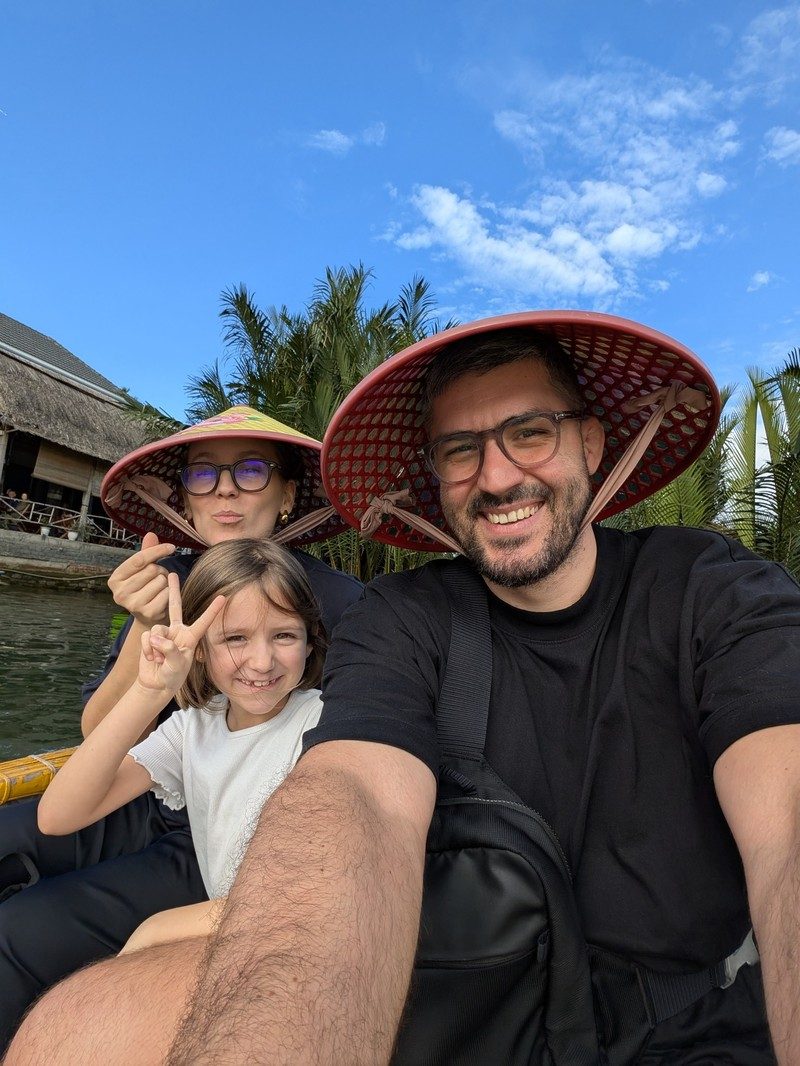 Famille souriante en bateau panier à Hoi An, Vietnam, portant les chapeaux traditionnels vietnamiens.