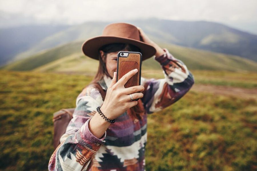 Randonneuse prenant un selfie avec son smartphone dans un paysage de montagne