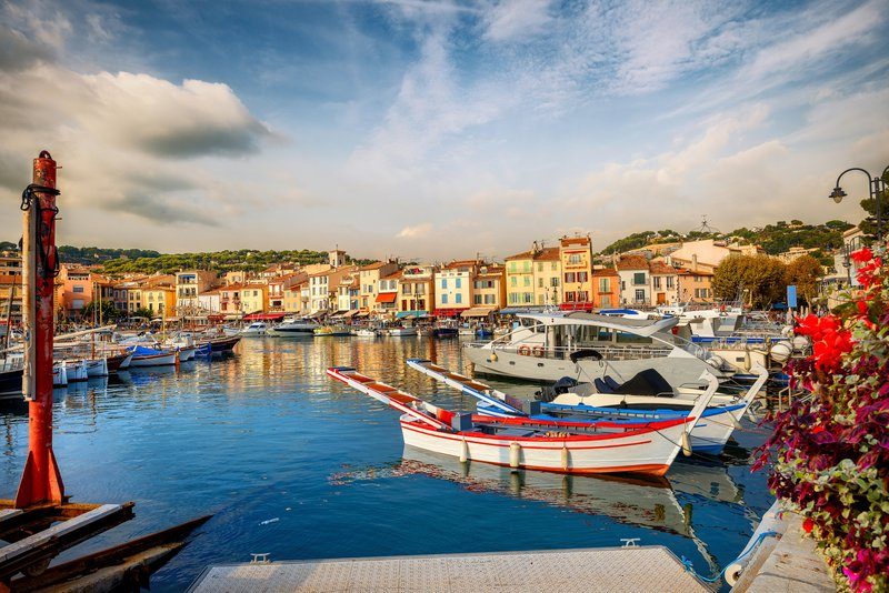 Le port de Cassis avec ses bateaux colorés et ses bâtiments en arrière-plan.