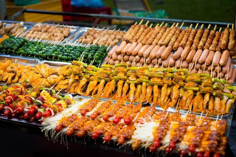Étals de street food avec brochettes de viande, légumes et fruits de mer au marché nocturne de Can Tho