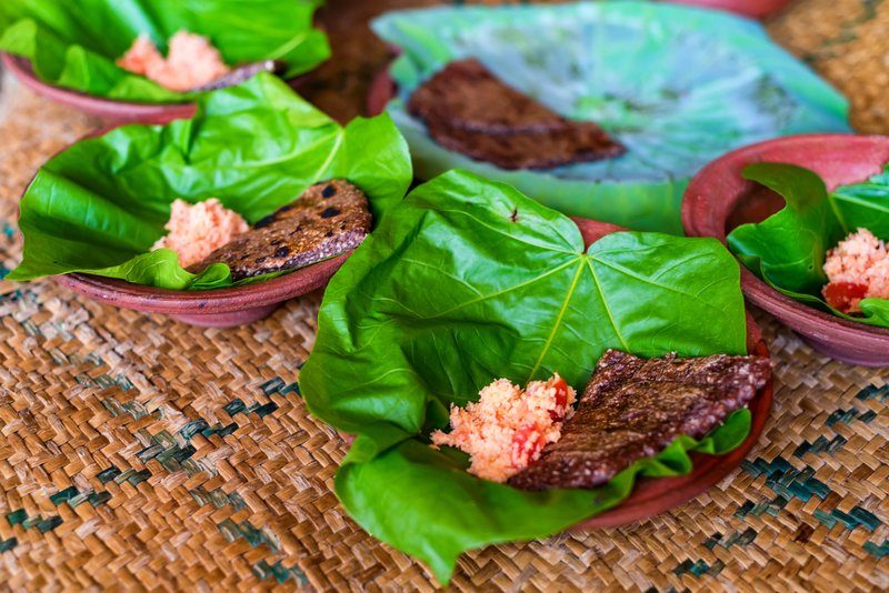 Plat traditionnel sri lankais servi sur une feuille verte, accompagné de pol sambol, une préparation à base de noix de coco râpée, piment et tomate, typique du Sri Lanka.