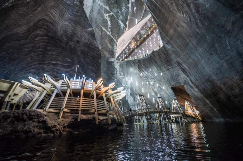 Vue intérieure impressionnante de la Salina Turda en Roumanie, un lieu spectaculaire avec des structures en bois éclairées sur l'eau.