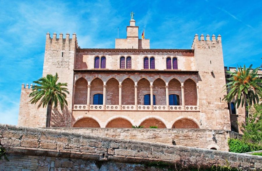 Façade majestueuse du Palais Royal de l’Almudaina à Palma de Majorque sous un ciel bleu.