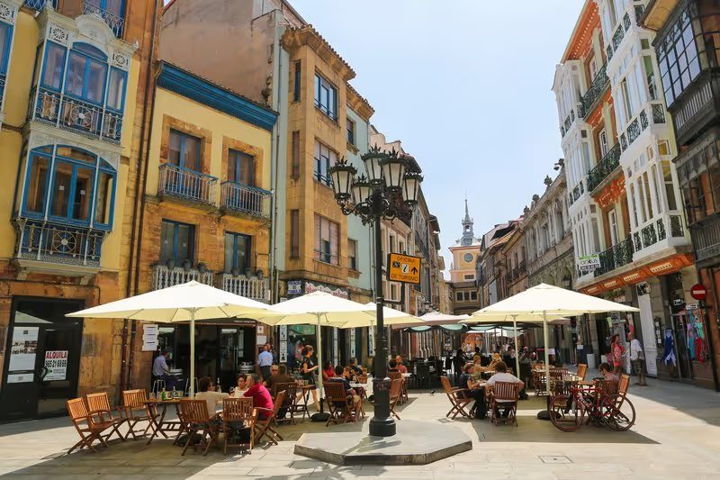 Rue animée d’Oviedo avec des terrasses de café et des bâtiments traditionnels.
