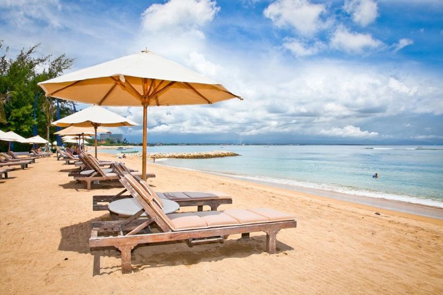 Plage de Sanur avec des transats alignés face à la mer calme de Bali.