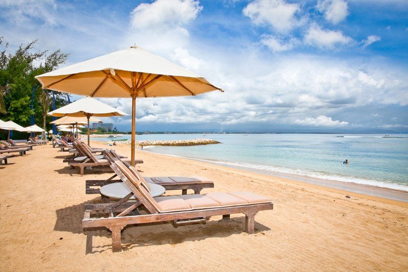 Plage de Sanur avec des transats alignés face à la mer calme de Bali.