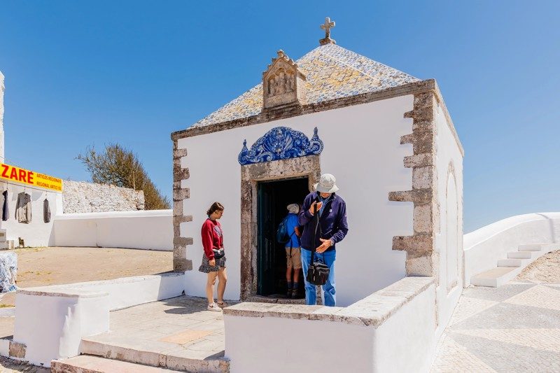 La chapelle Ermida da Memória, un site historique de Nazaré, Portugal, sous un ciel bleu éclatant.