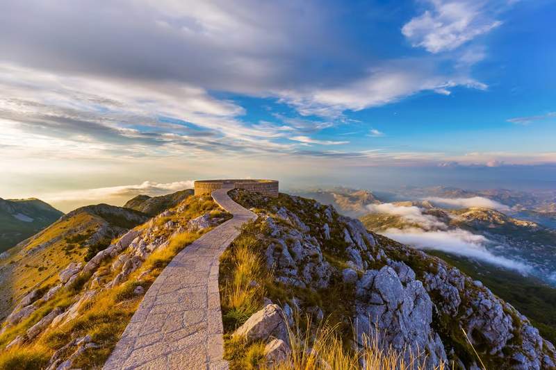 Sentier pavé menant au mausolée de Njegoš au sommet du mont Lovćen, vue panoramique sur les montagnes du Monténégro au lever du soleil